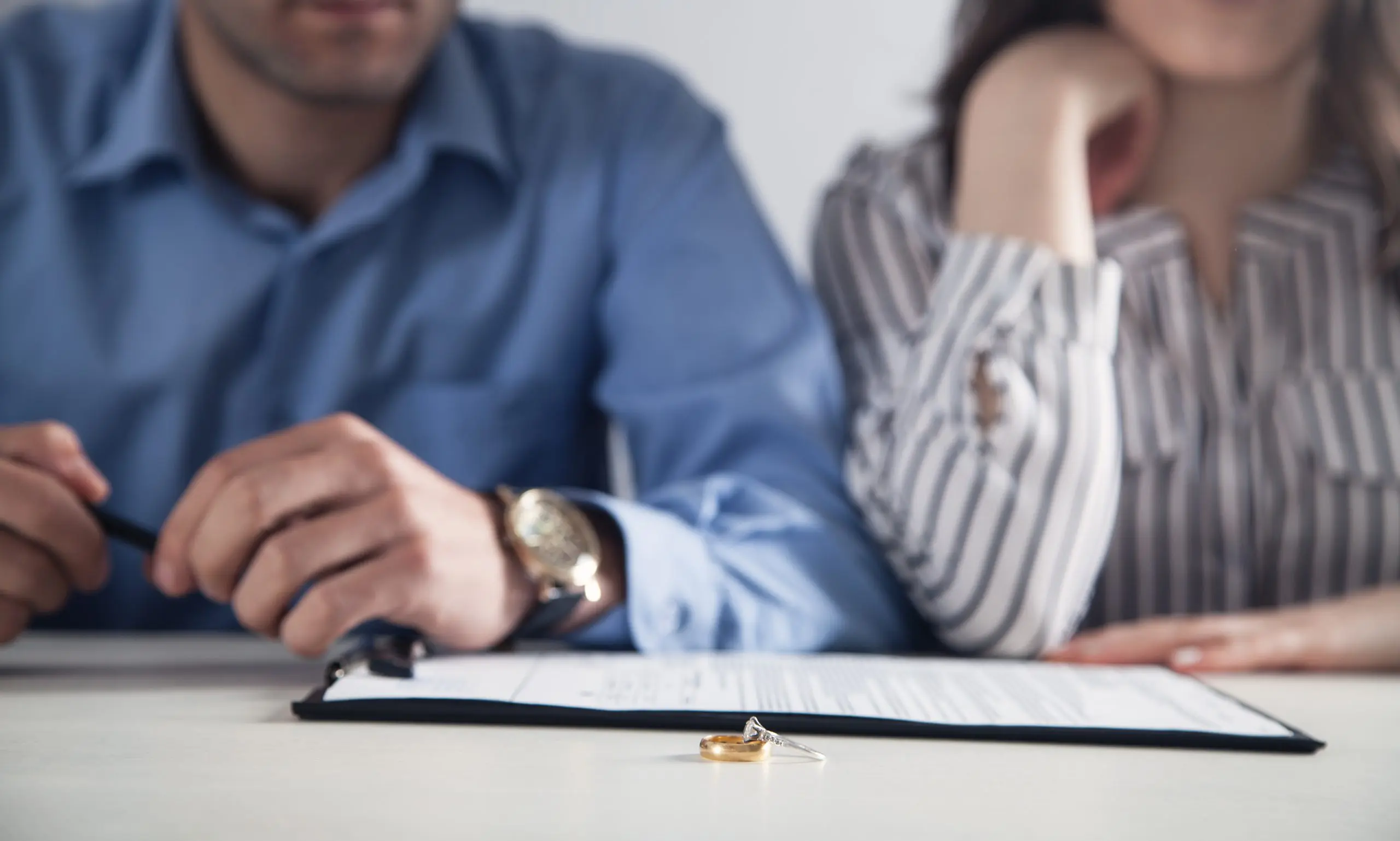 Couple with divorce contract and ring on desk