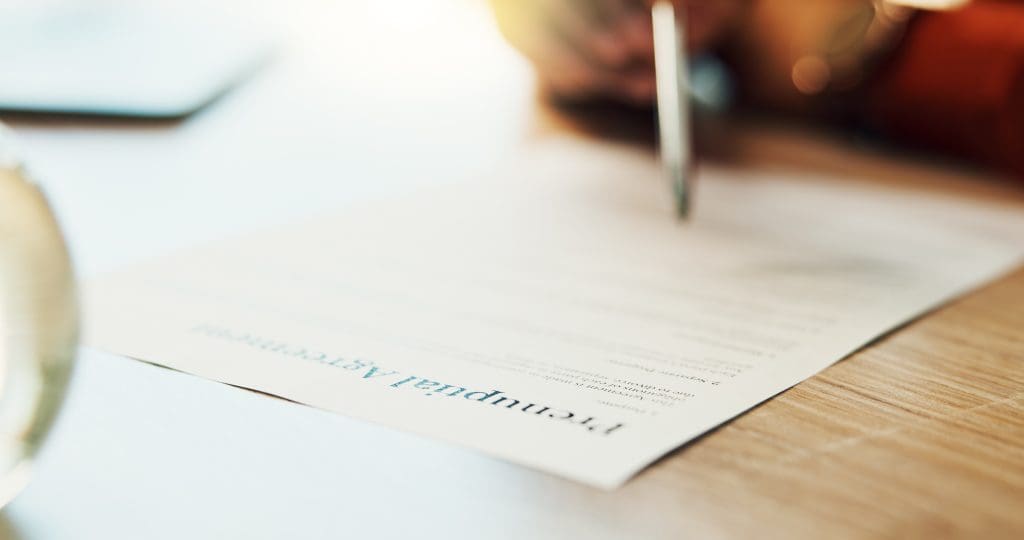 Closeup of hands signing a prenuptial agreement