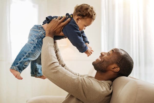 Caring father smiling and amusing his son while sitting on the couch