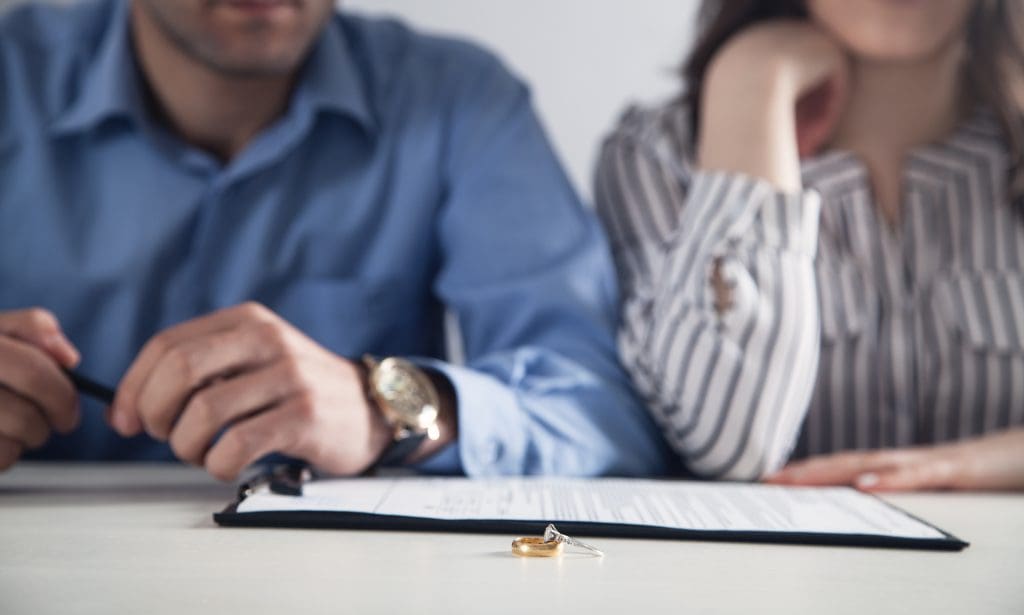 Couple with divorce contract and ring on desk