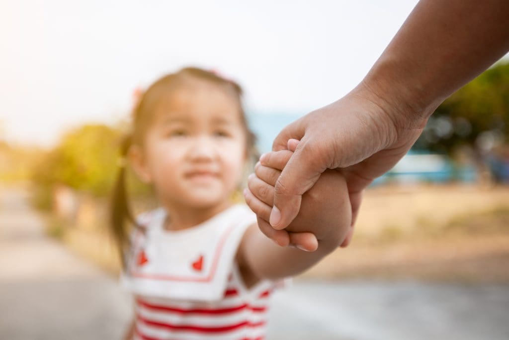 Parent and child holding hands together with love and care