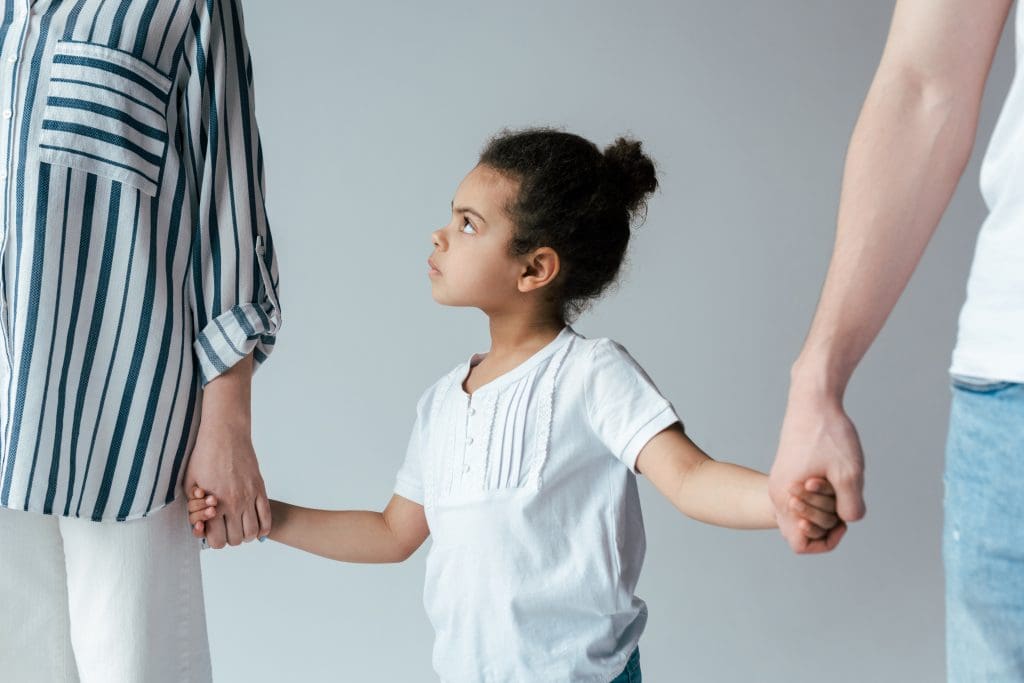 Sad young girl holding hands with divorced foster parents