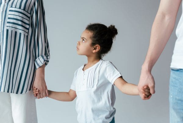 Sad young girl holding hands with divorced foster parents